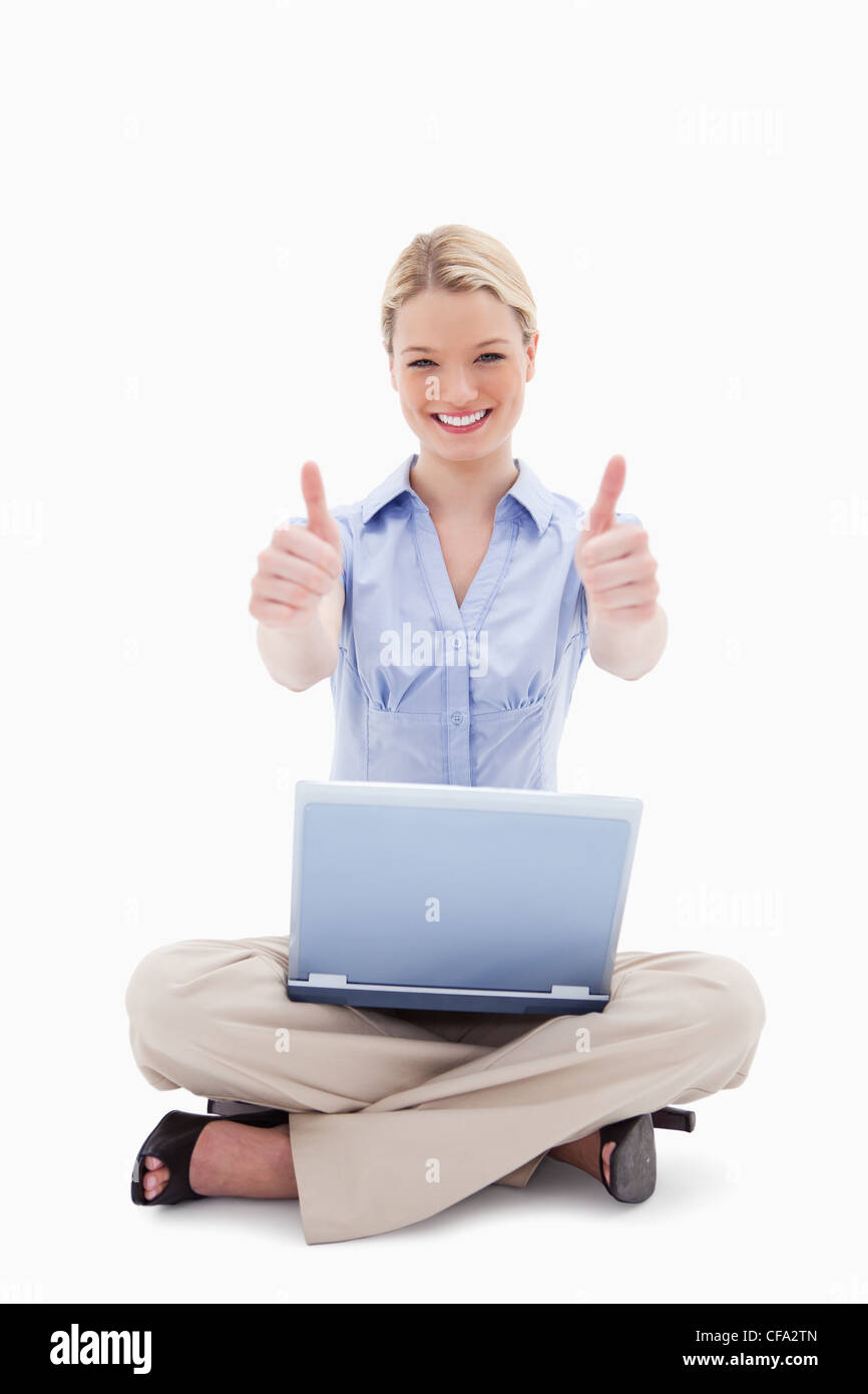 Sitting woman with laptop giving thumbs up Stock Photo