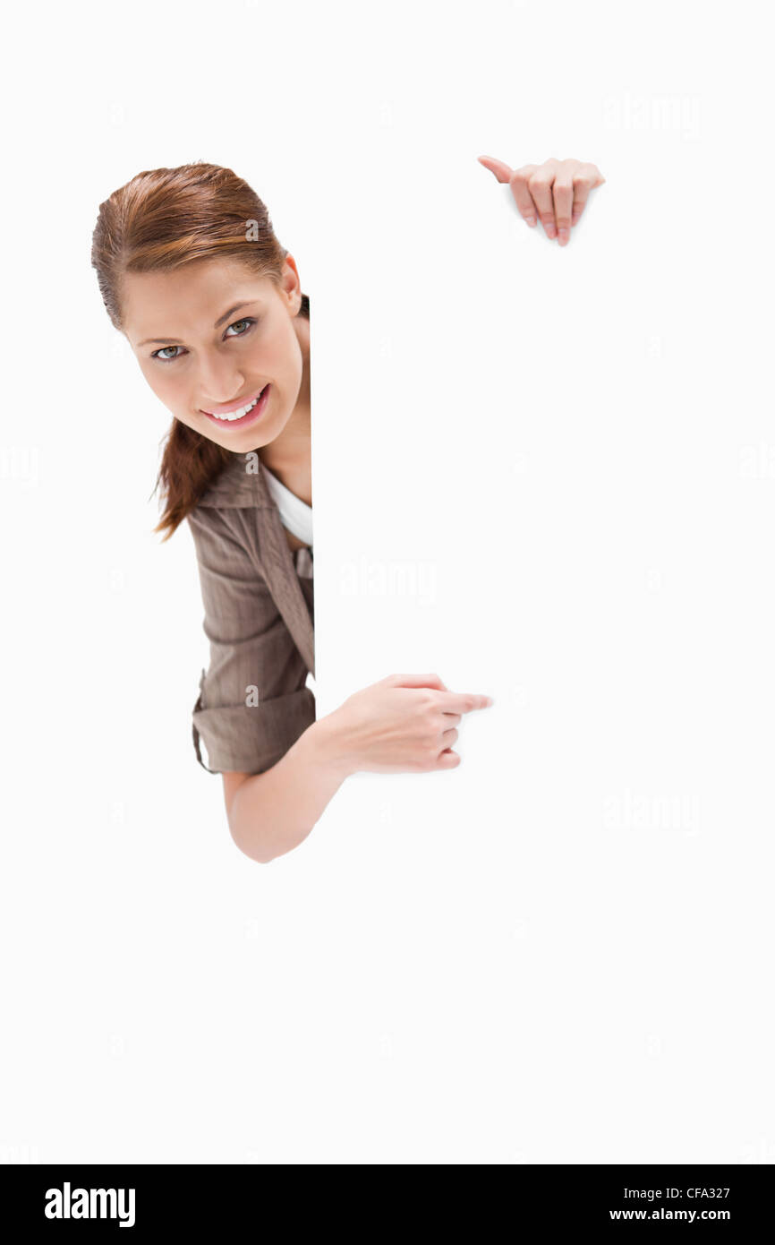 Smiling woman pointing around blank sign Stock Photo