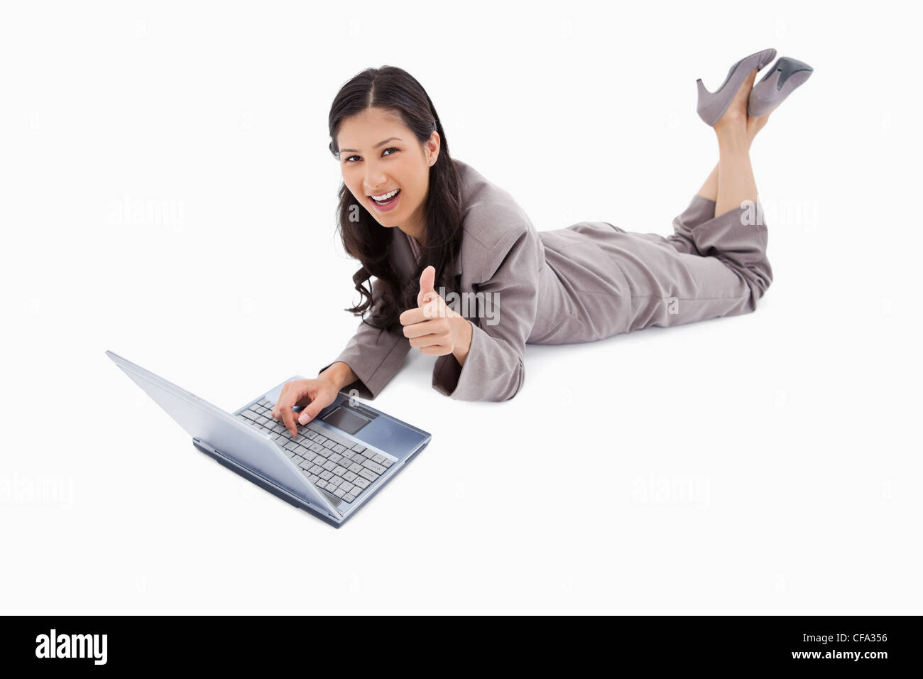 Lying woman with laptop giving thumb up Stock Photo