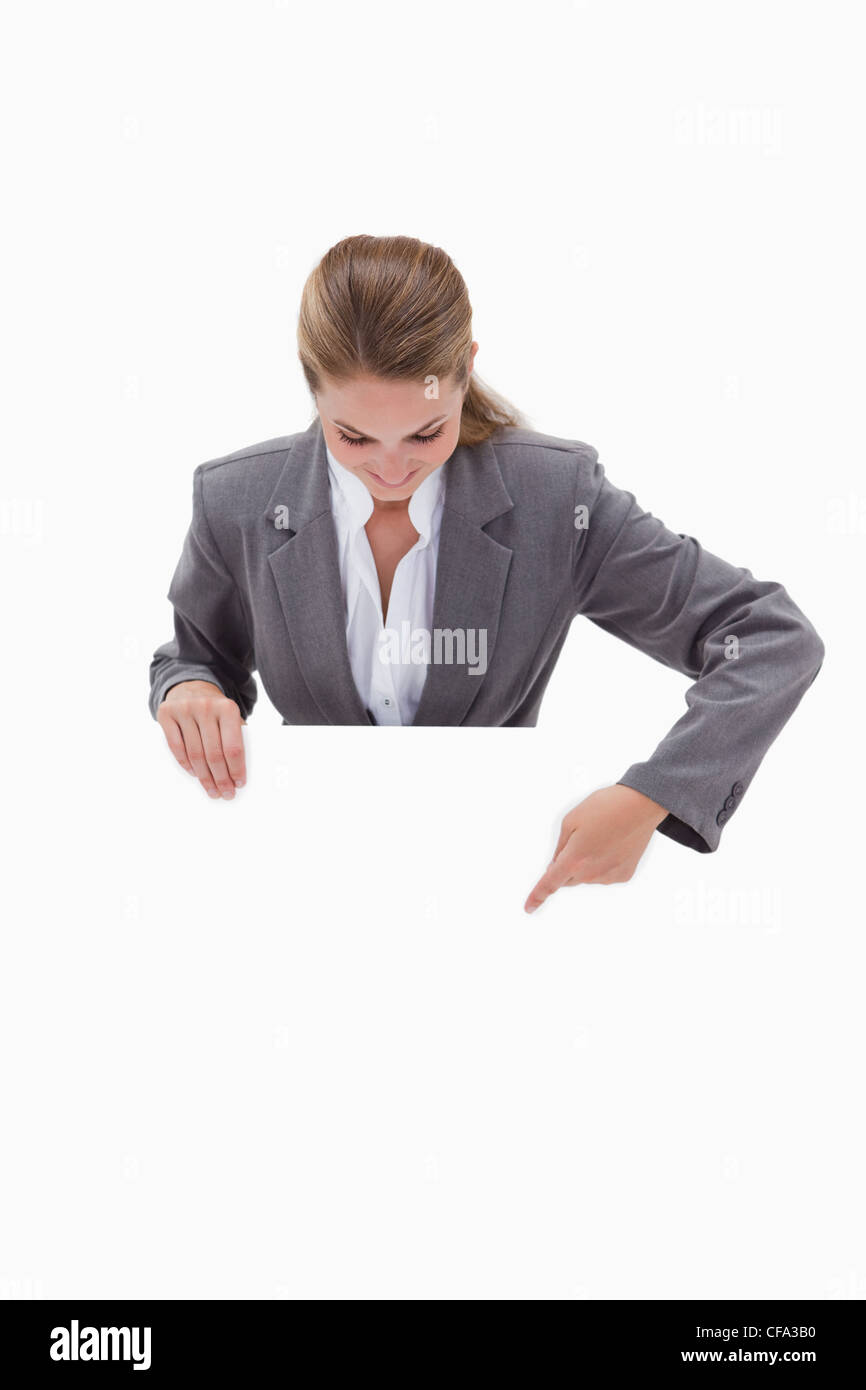 Bank employee pointing down at blank sign in her hands Stock Photo