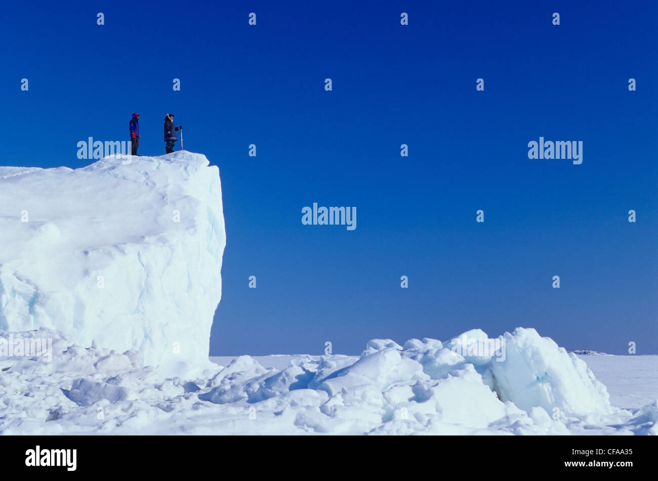Inuit guide and client on iceberg frozen in sea ice, Kimmirut, Baffin