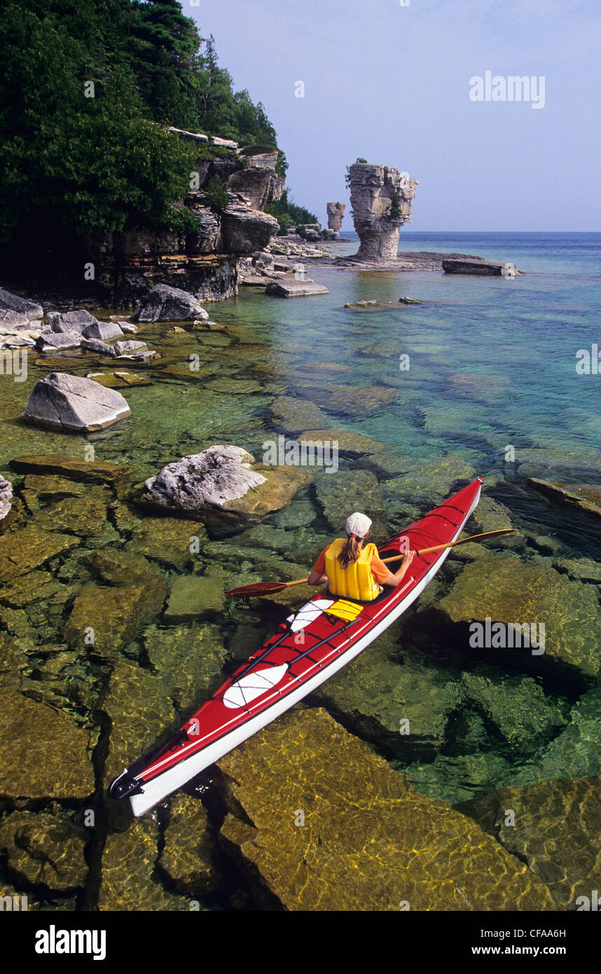 Young woman sea kayaking past Flowerpot Island, Fathom Five National