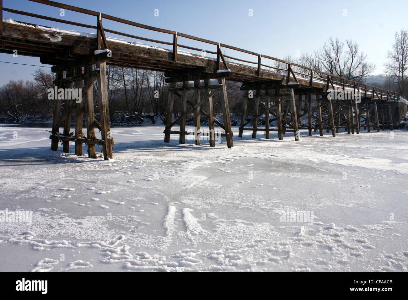 Frozen river under the old wooden bridge. Stock Photo