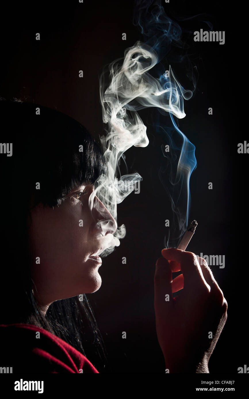 Illuminated profile of woman smoking Stock Photo