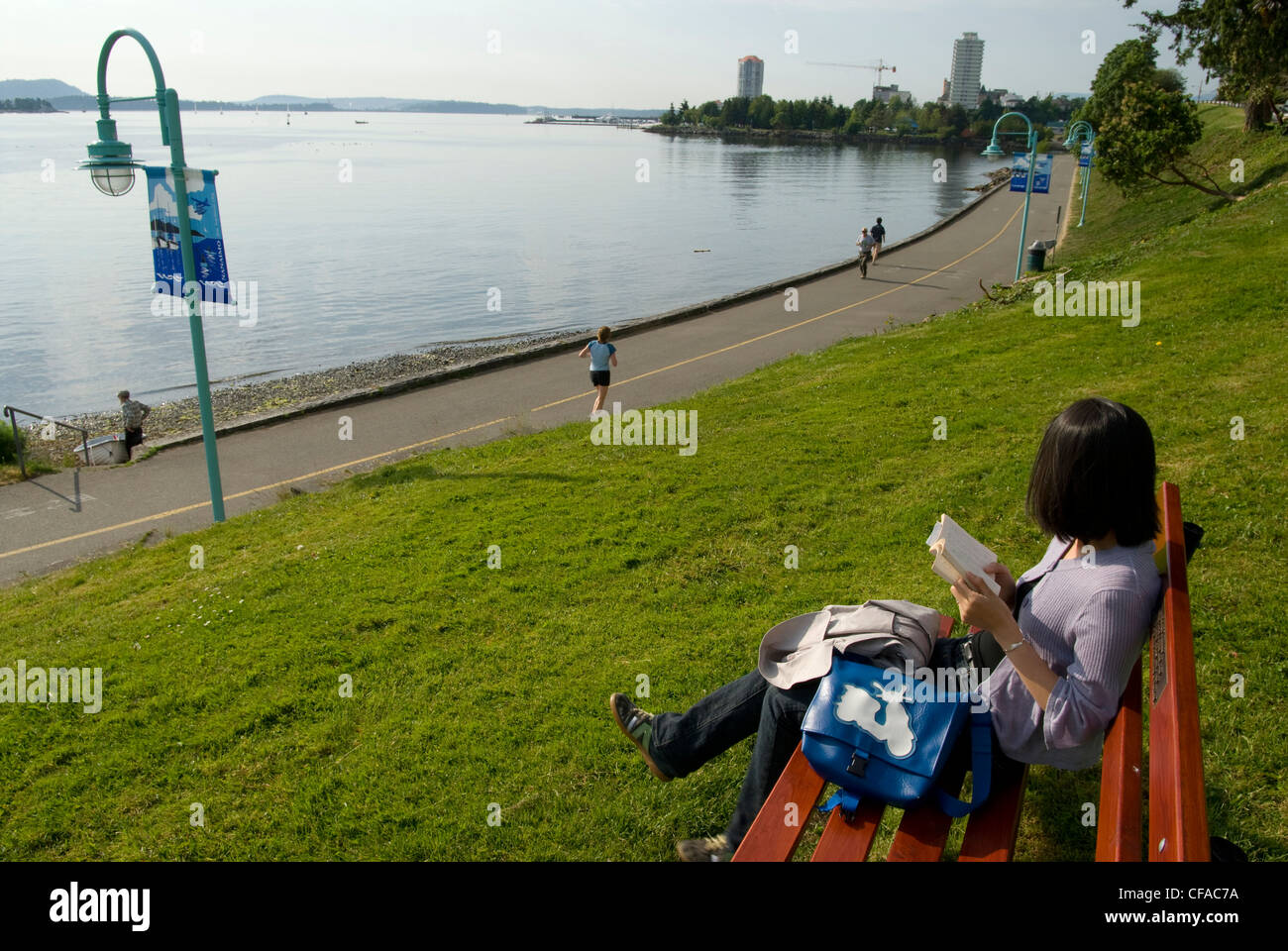 Woman reading a book along Harbour front walkway. Nanaimo, British Columbia, Canada. Stock Photo