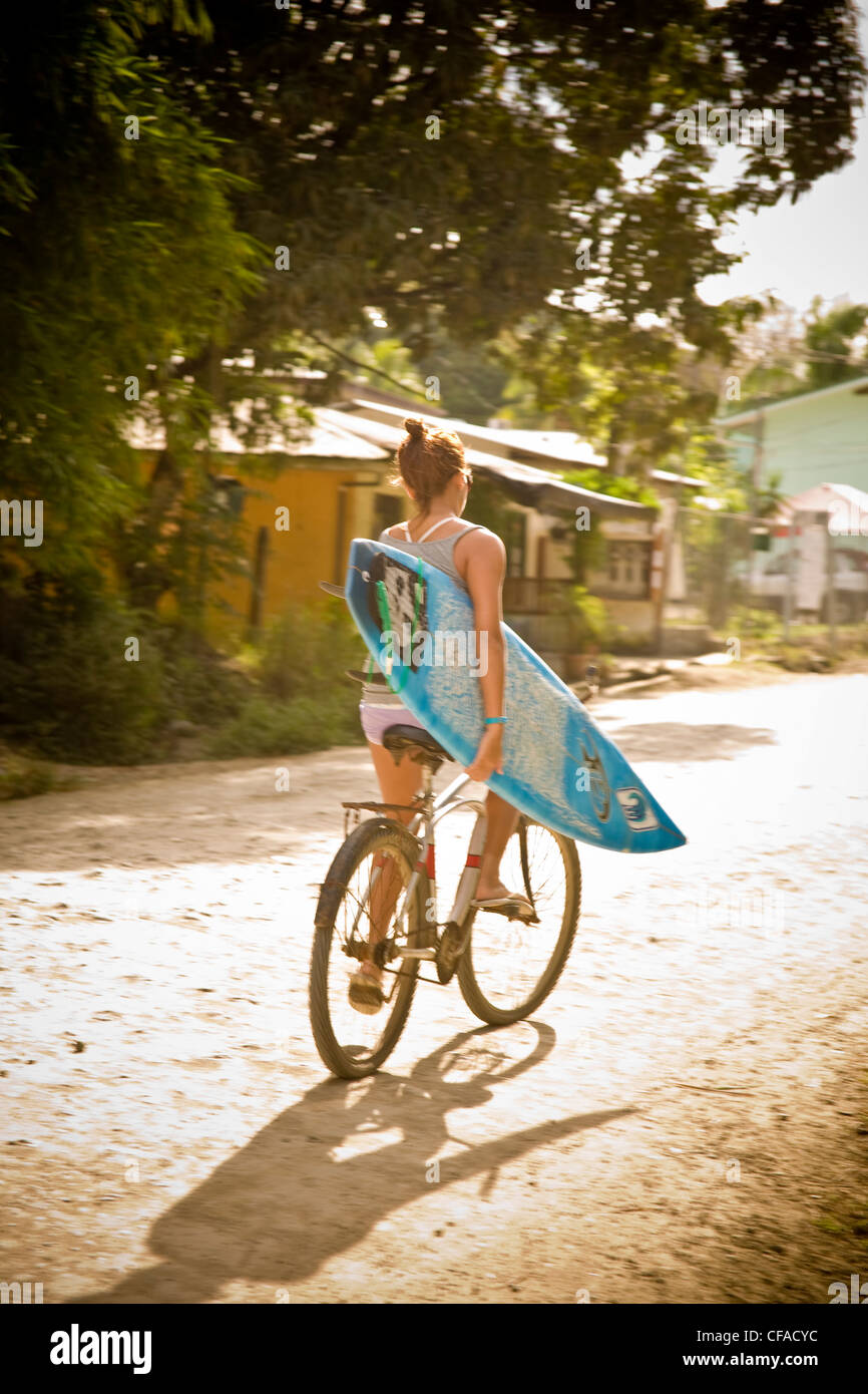 A young woman biking to the surf in Mal Pais, Costa Rica Stock Photo