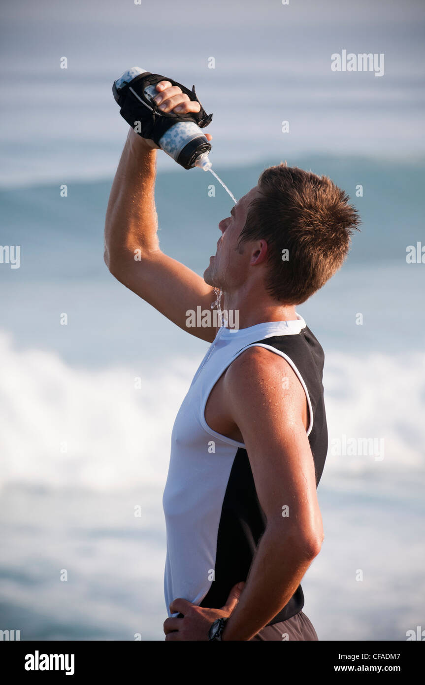 Runner pouring water on head on beach Stock Photo Alamy