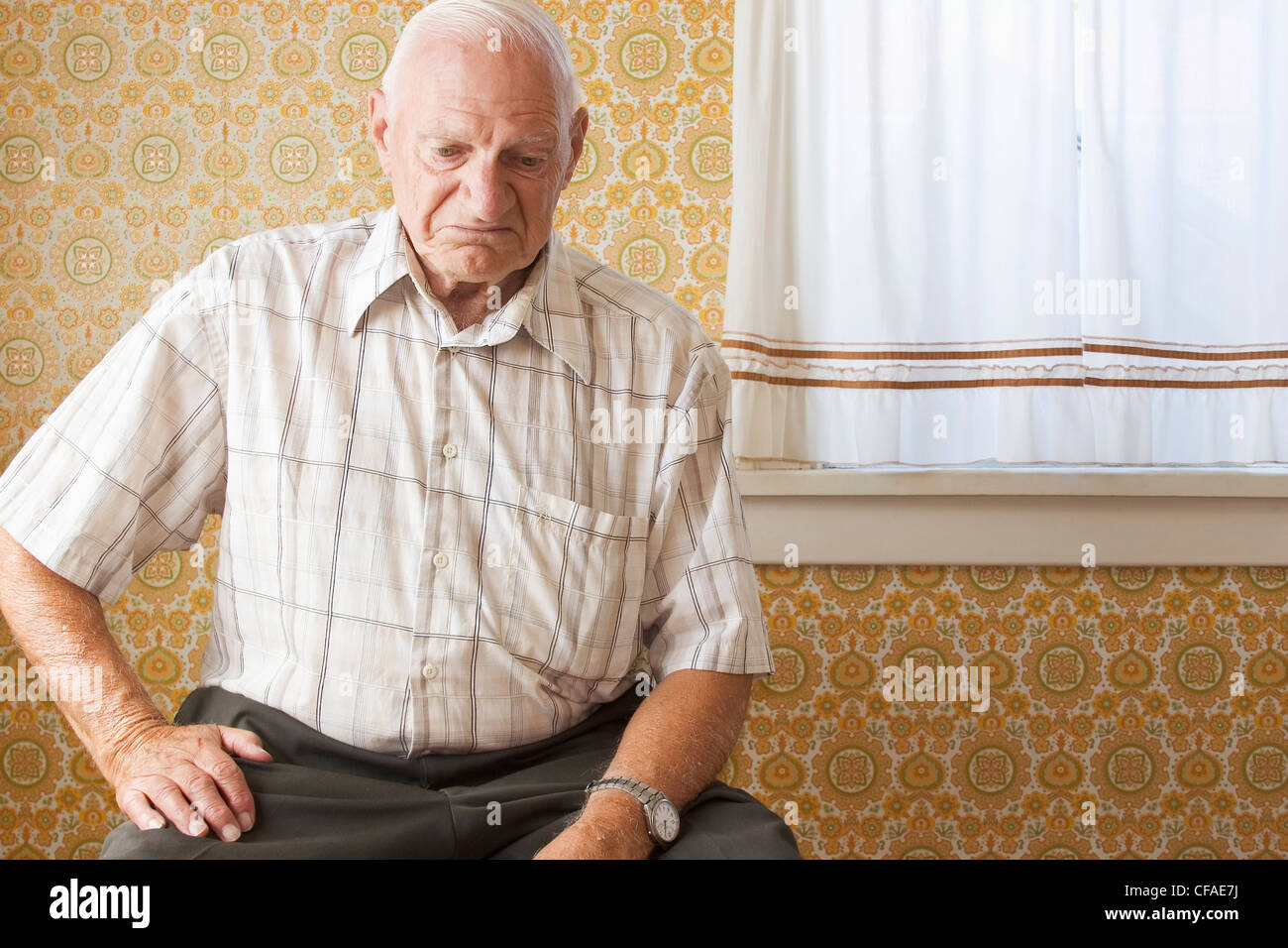 senior citizen (70-80 years old) sitting on chair in vacant house, Canada. Stock Photo