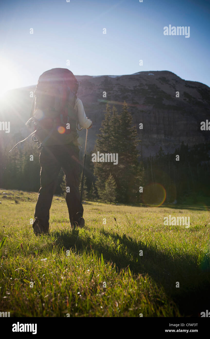 Hiker carrying pack on grassy hillside Stock Photo Alamy