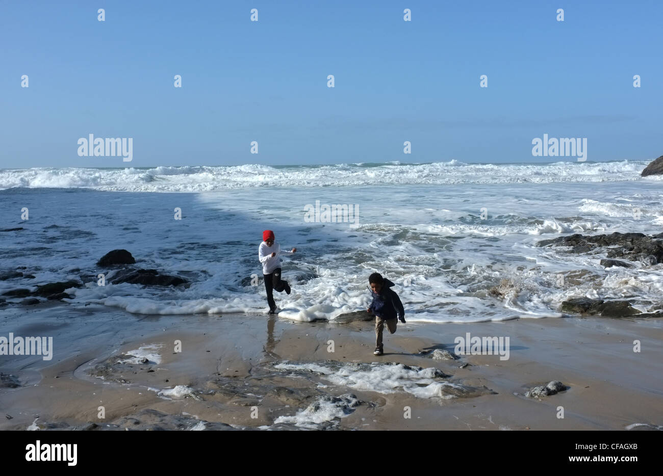 Two young black children playing on the beach at St Agnes, Cornwall, UK Stock Photo