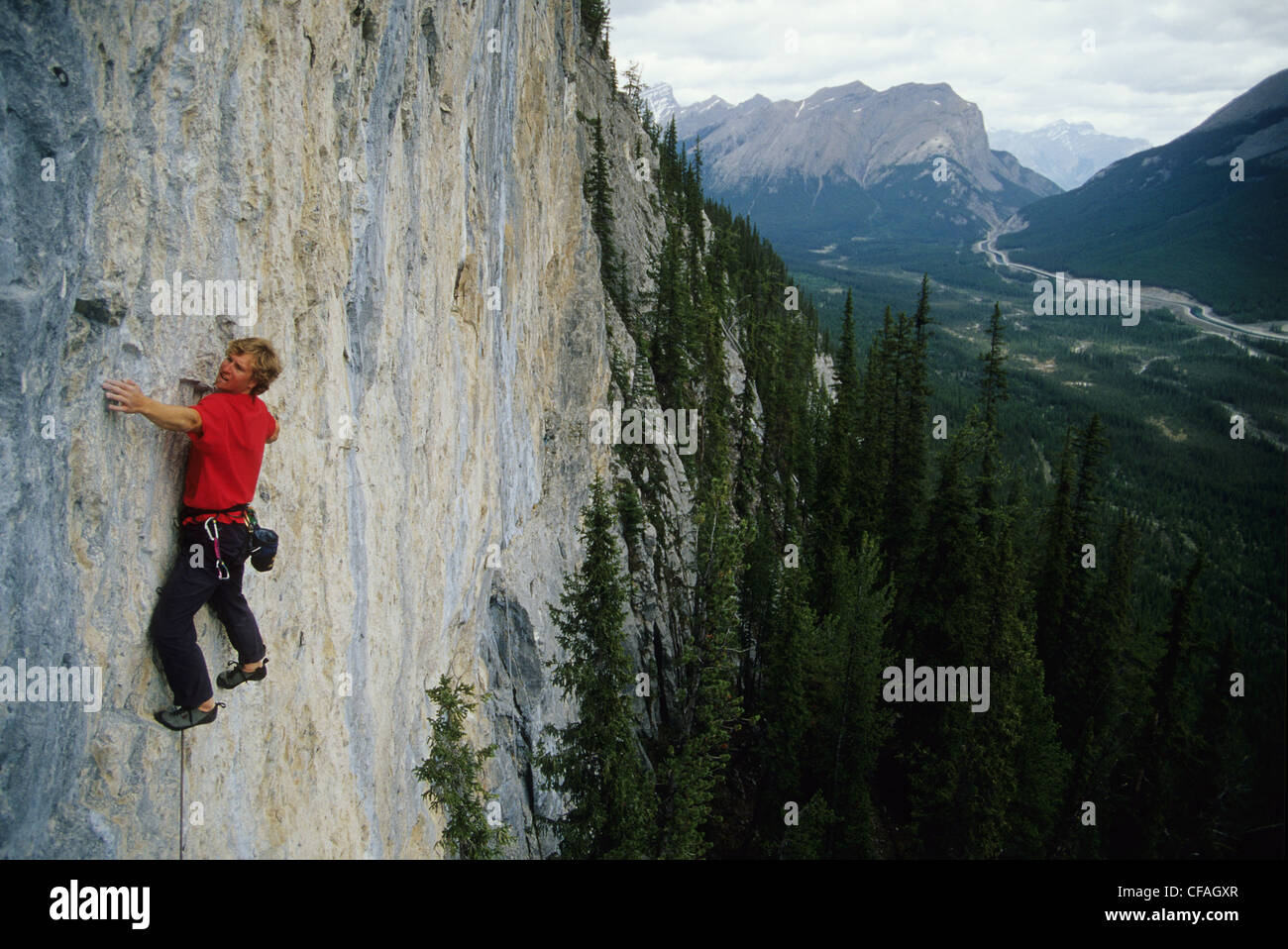 a young man leading up a route called Weapons of Mass Destruction in Spray Lakes, Alberta, Canada. Stock Photo