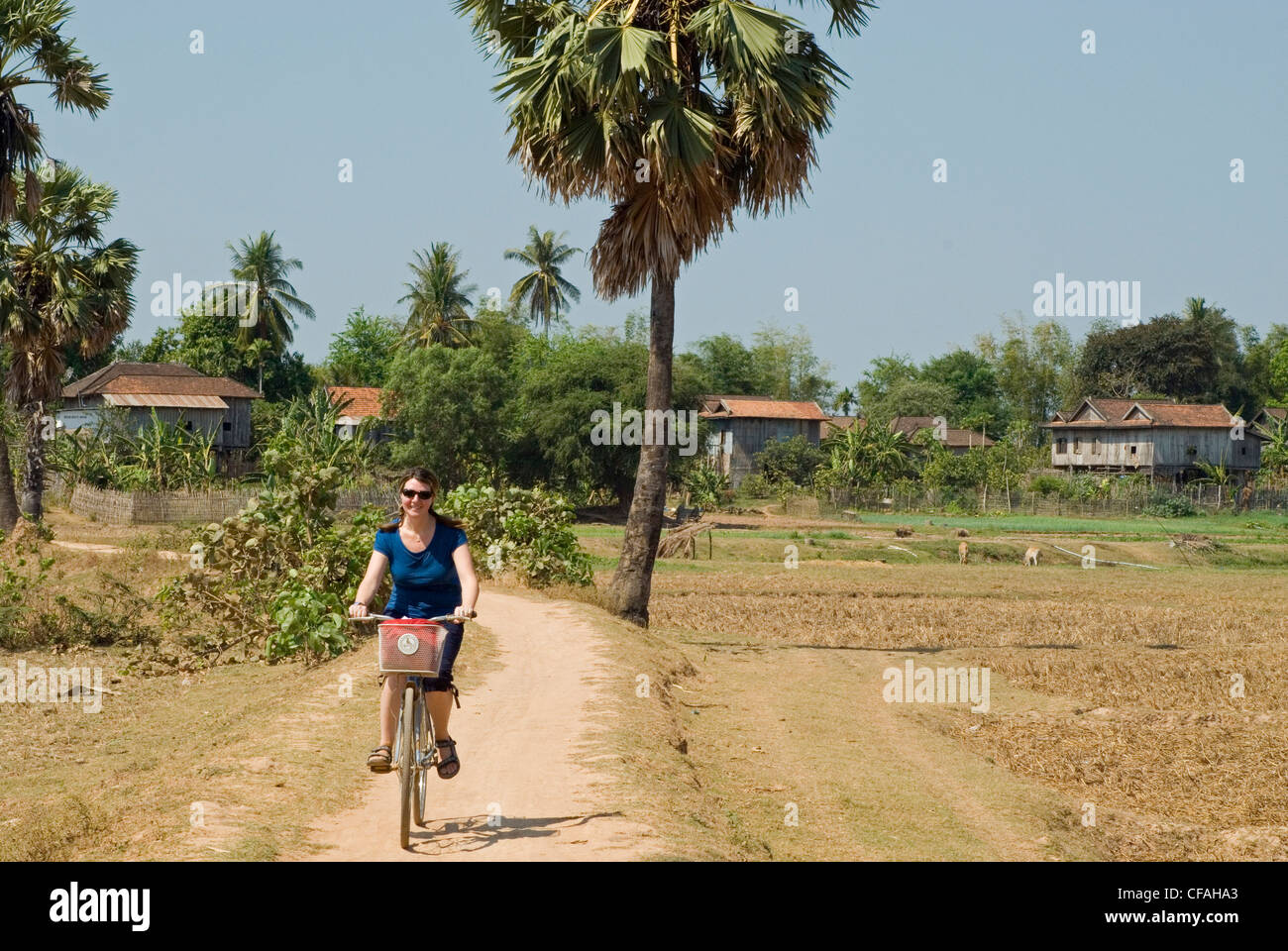 Woman pedaling her bike along the trails of Koh Trong Island on the Mekong River, Kratie, Cambodia. Stock Photo