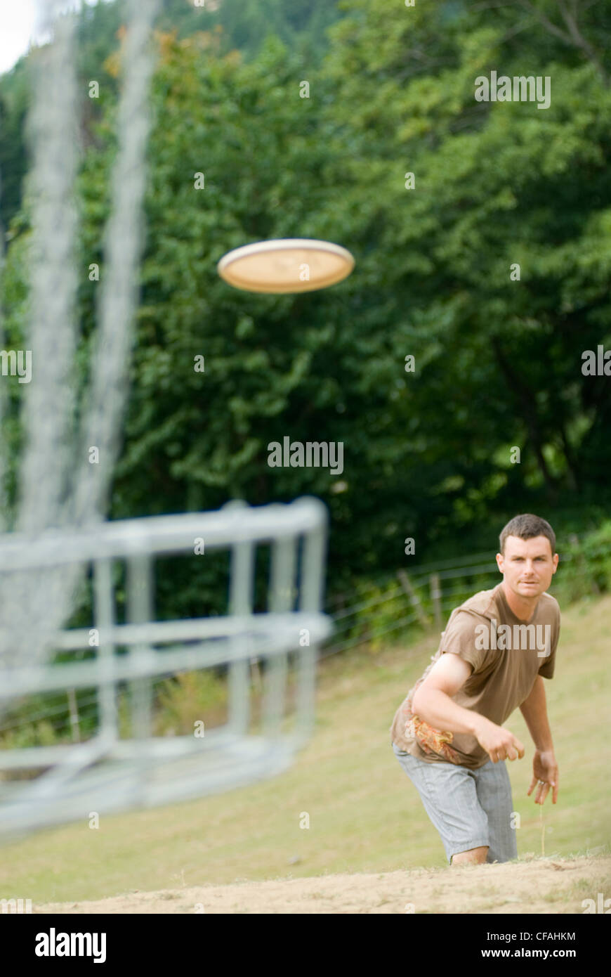 Man putting with frisbee while playing a round of disc golf, near Victoria, British Columbia