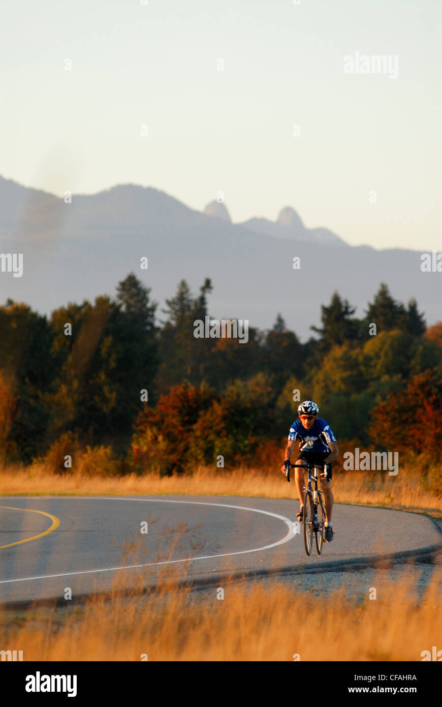 Man road cycling at Iona Beach Regional Park. Richmond, British Columbia, Canada Stock Photo