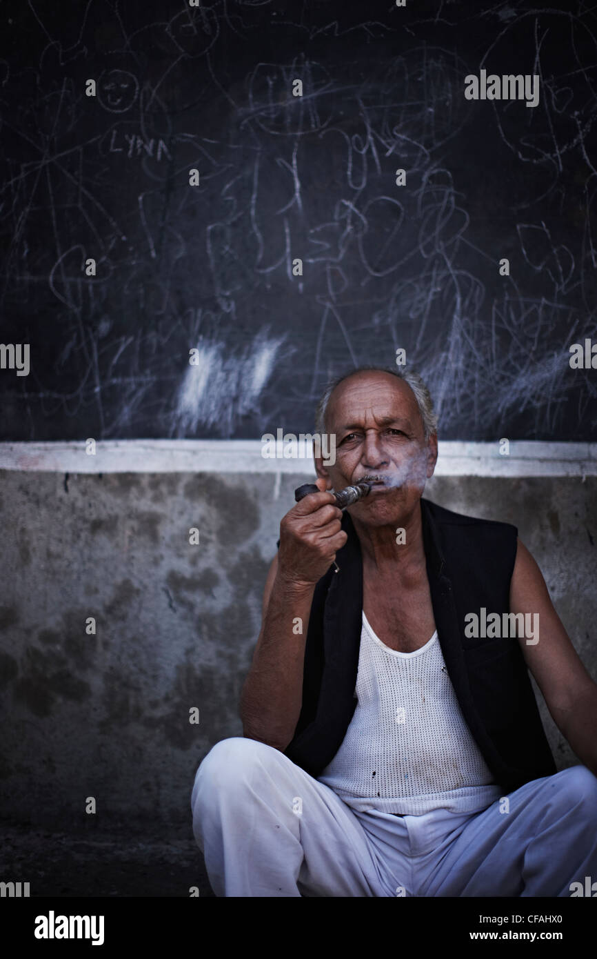 Man smoking pipe on city street Stock Photo