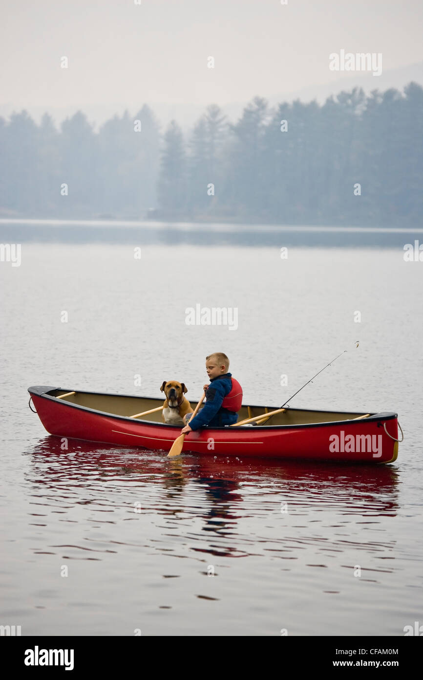 Young boy going fishing with dog in canoe on Source Lake, Algonquin Provincial Park, Ontario, Canada. Stock Photo