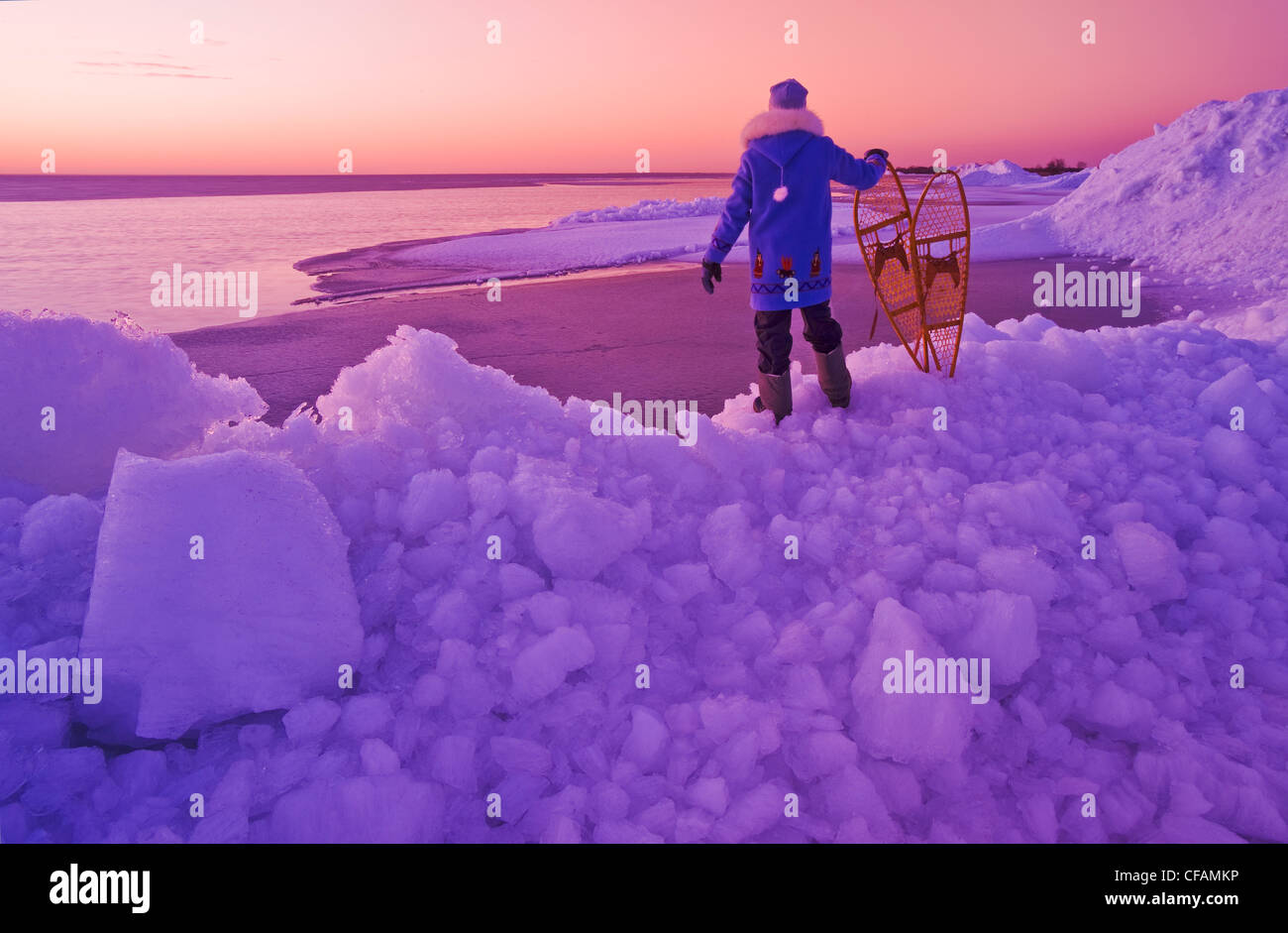 a man with snowshoes looks out over washed up ice piles, along Lake