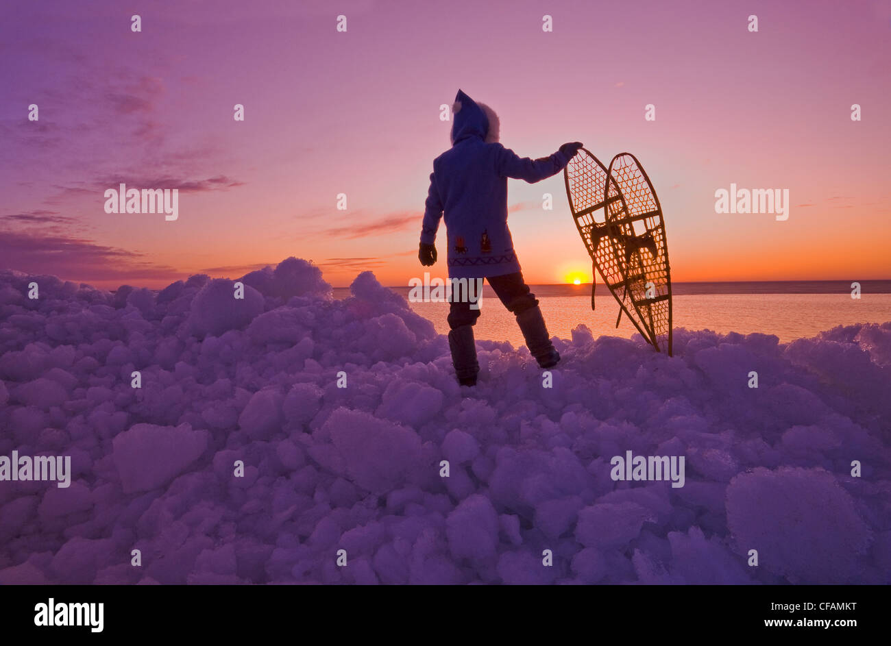 a man with snowshoes looks out over washed up ice piles, along Lake