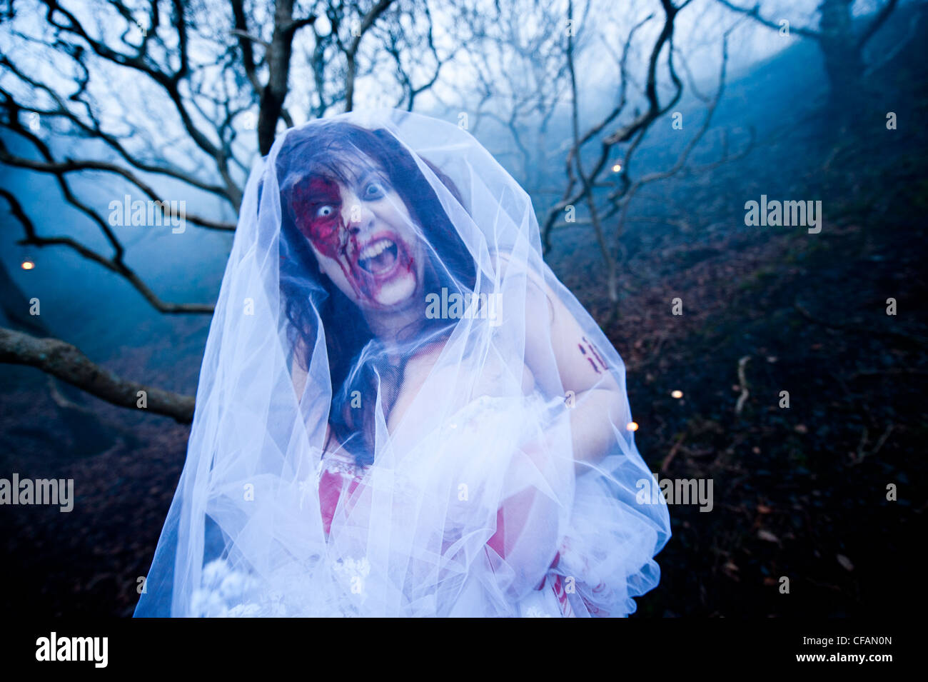 A young woman in full make-up taking part in a Zombie bride 'trash the wedding dress' Stock Photo
