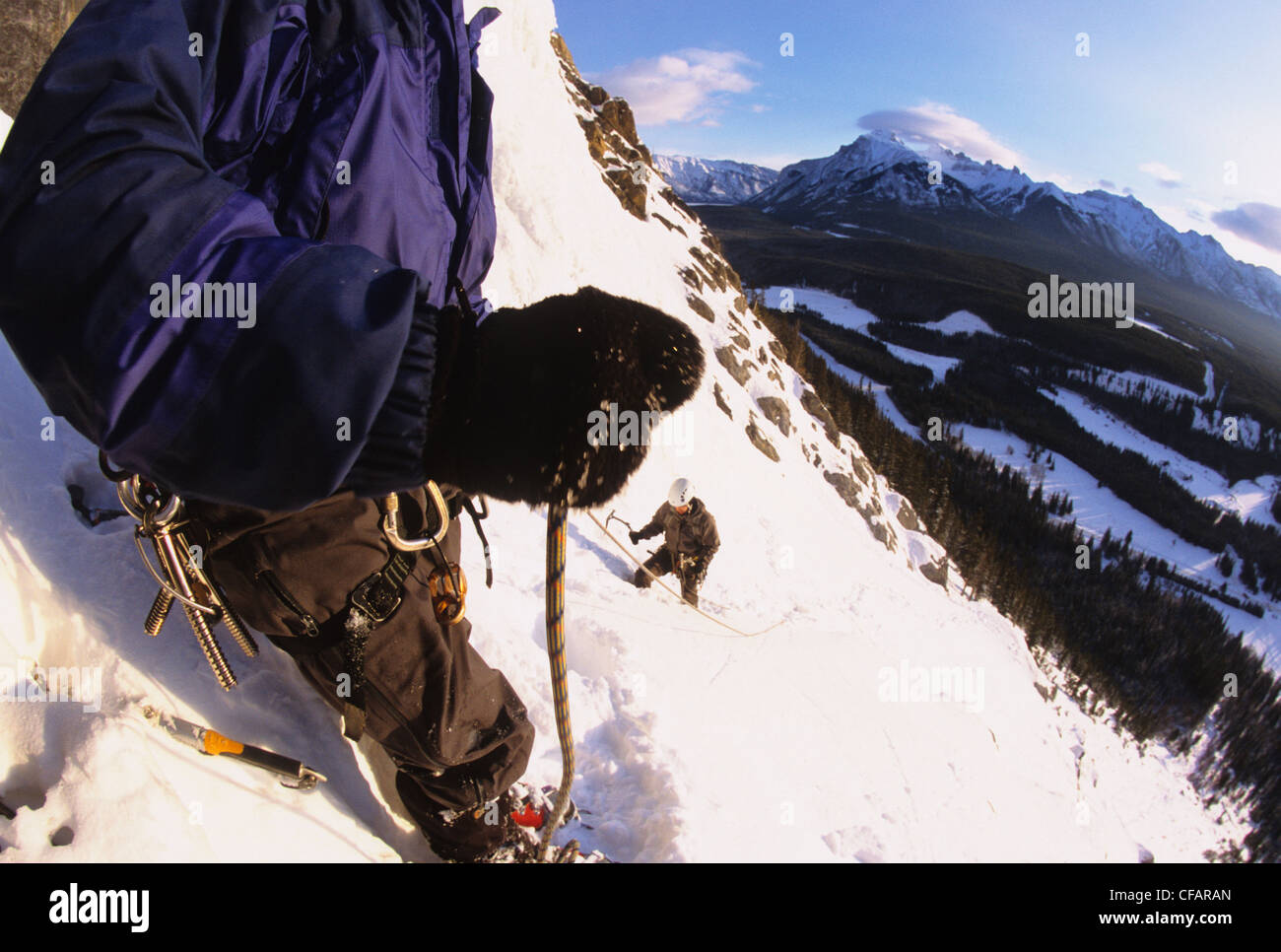 An ice climber belaying his partner on Cascade Falls WI 3, Banff