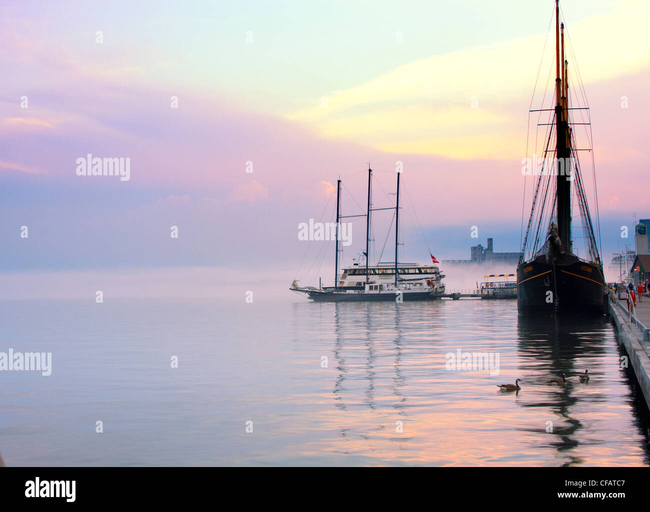 Sailing ship and tour boat docked at Toronto waterfront at dusk