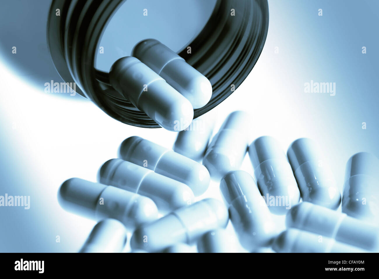 Pills in blue tones pouring out of a bottle in horizontal format Stock Photo
