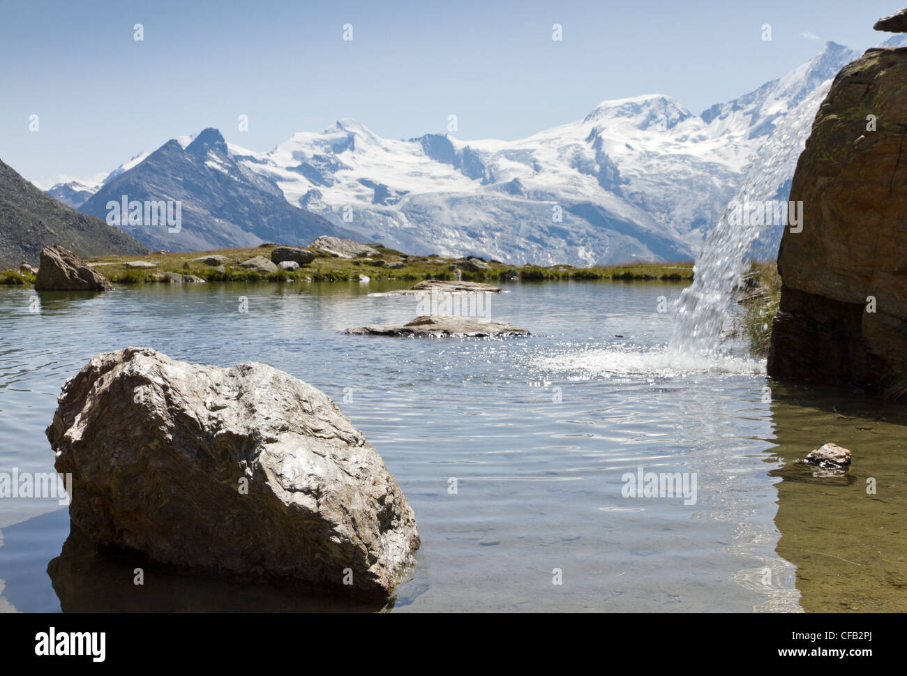 high alpine lake with litlle waterfall in summer, Saas Fee, Switzerland Stock Photo
