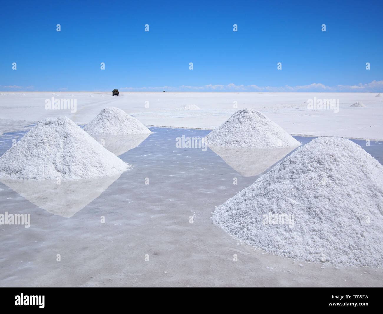 Piles of drying salt and reflection in the water at the Salar de Uyuni (salt flats) in Bolivia. Stock Photo