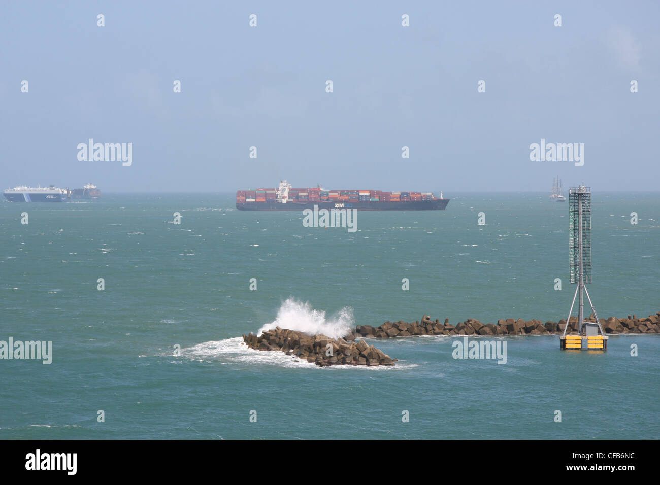 Waves splash on the breakwaters at Colon, Panama, with freighters in the distance. Stock Photo