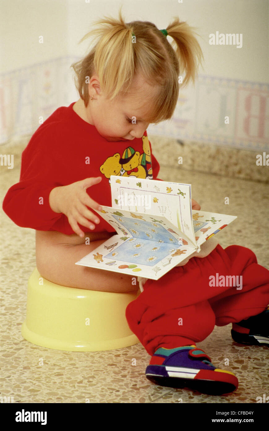 Female child with blonde hair in bunches sitting on potty reading book  Stock Photo - Alamy