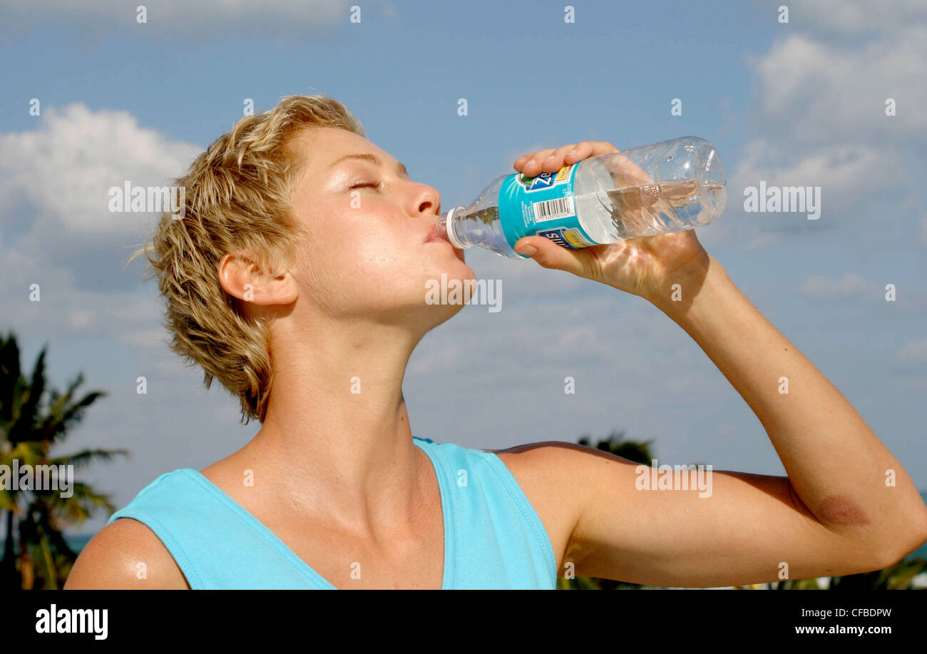 Female Short Blonde Hair Wearing Turquoise Vest Top Drinking From