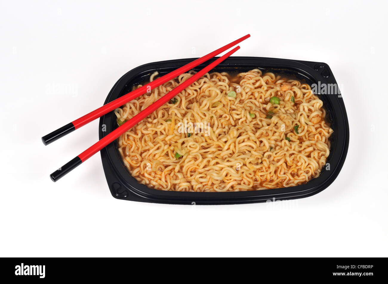 Oriental noodles with peas in black plastic tray with chopsticks on white background cut out Stock Photo