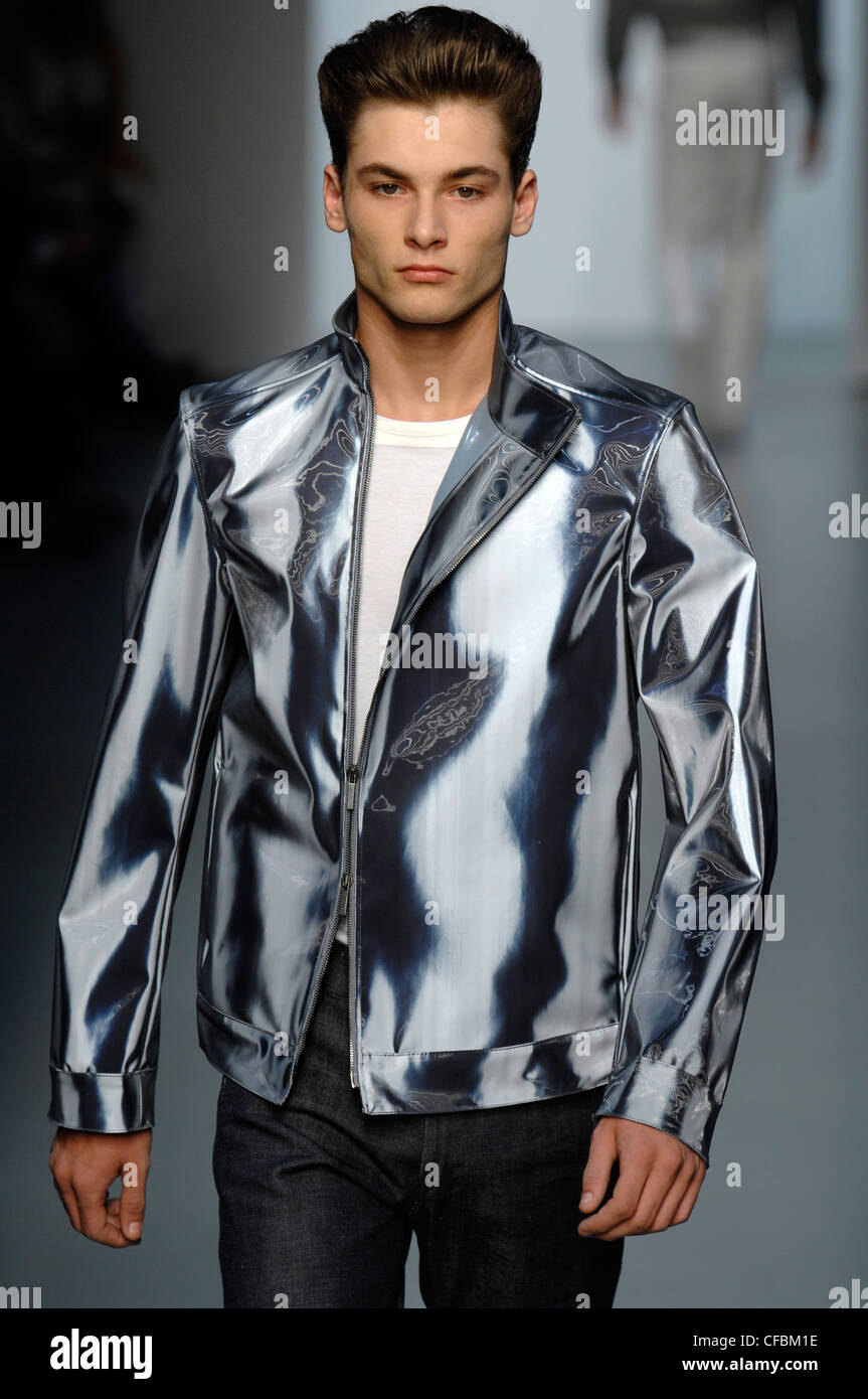 Calvin Klein Milan Menswear Ready to Wear Spring Summer Model wearing silver jacket with white t shirt and grey jeans Stock Photo