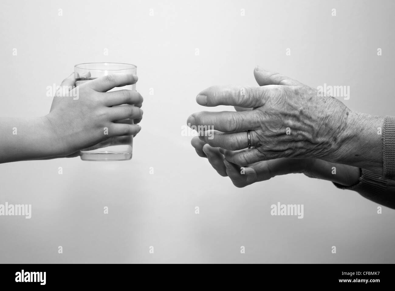 hands of grandmother and grandchild with the glass of water Stock Photo