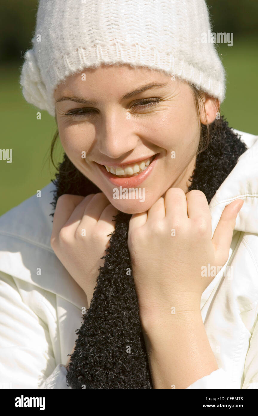 Female wearing white coat, black scarf and white wool hat with flower