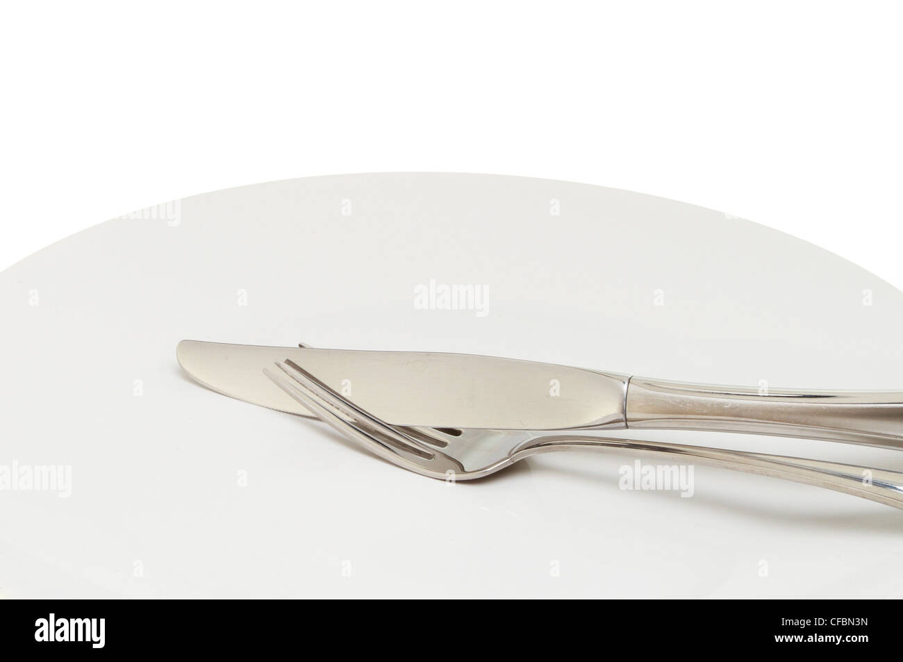 Closeup of a stainless steel knife and fork on a plate Stock Photo