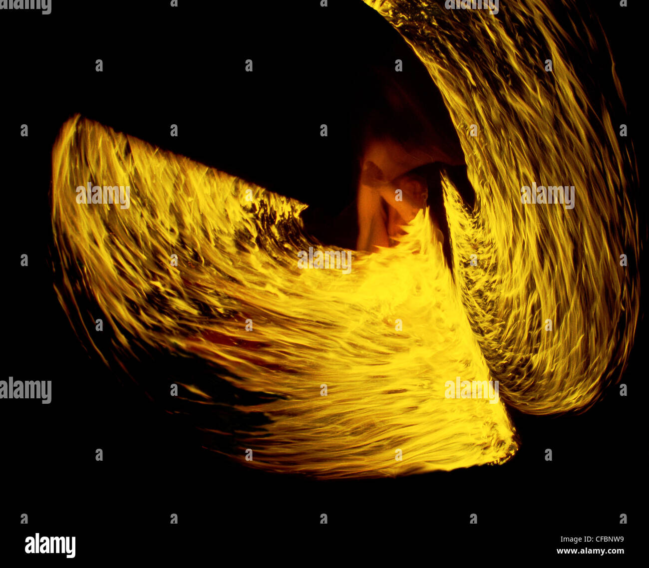 Fire dancer displaying flaming swords which look like fiery wings Stock