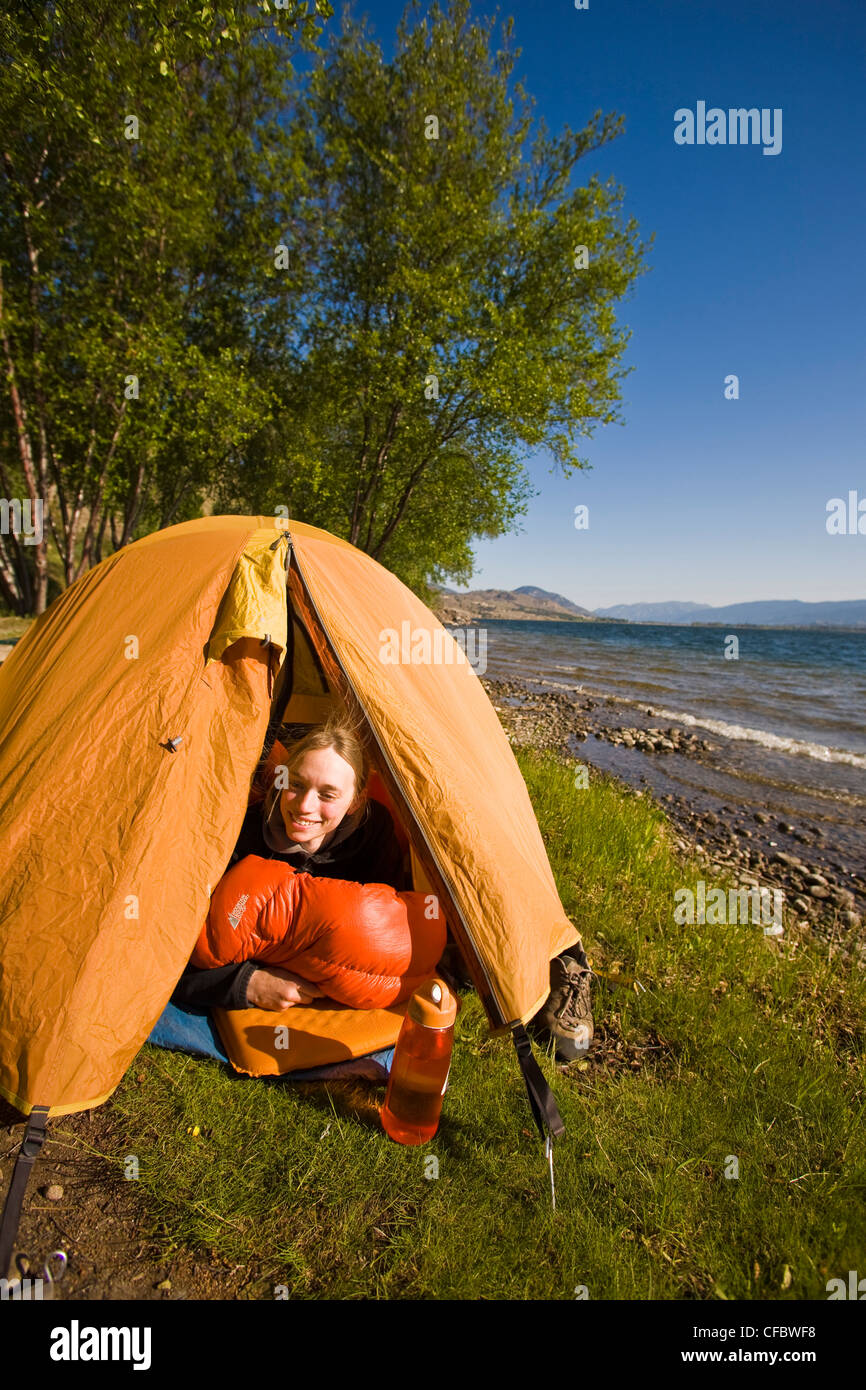 A young woman lying down in tent, Skaha lake, Penticton, British Columbia, Canada Stock Photo