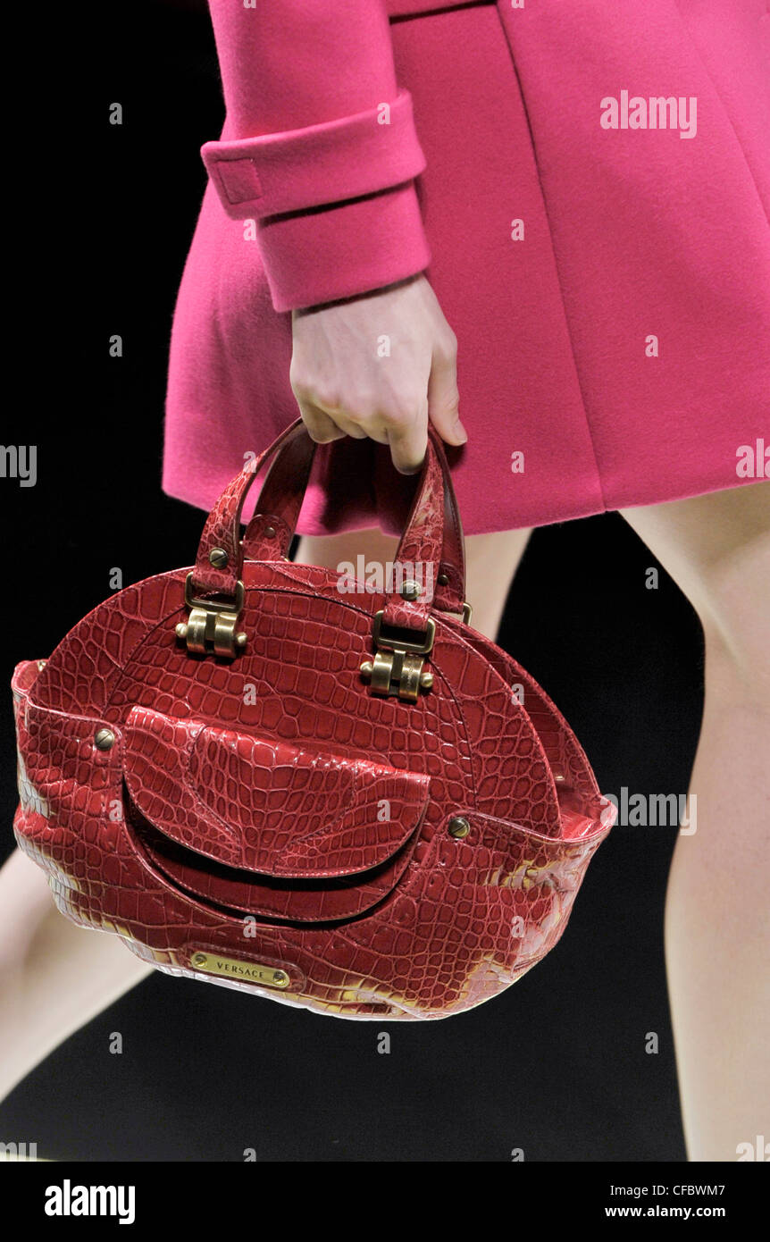 Versace Milan Ready to Wear Autumn Winter Model carrying red crocodile skin round shaped handbag side pocket and Versace name Stock Photo