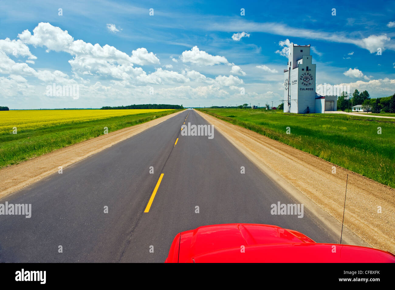 road going across the prairies with grain elevator in the background, near Culross, Manitoba, Canada Stock Photo