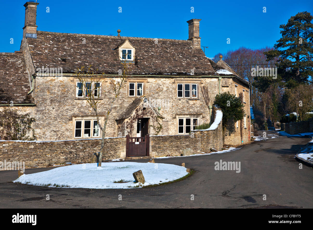 A pretty Cotswold stone cottage in the snow at Ampney St Peter, Gloucestershire, England, UK Stock Photo