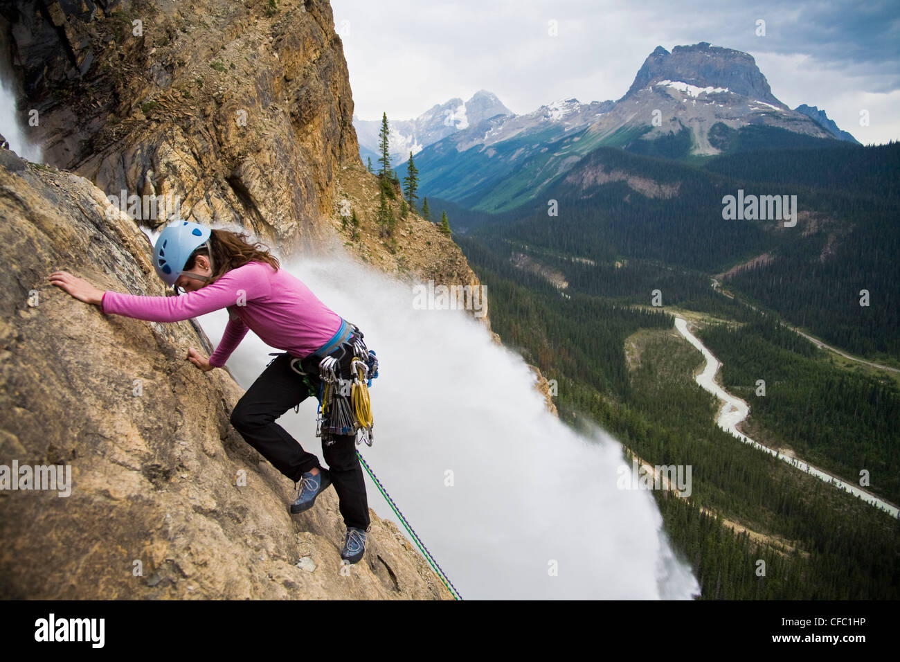 A female rock climber ascends the Takakkaw Falls route (5.6) in Yoho National Park, BC Stock Photo