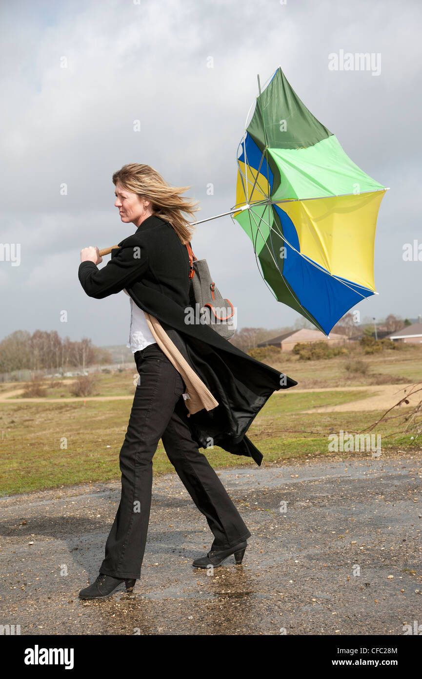 Woman struggles to hold onto her umbrella in a high wind Stock Photo
