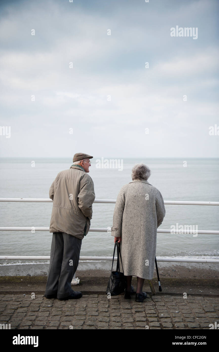 Grey Pound: A Rear view of an old elderly couple man and woman dressed in grey, on a seaside promenade UK Stock Photo