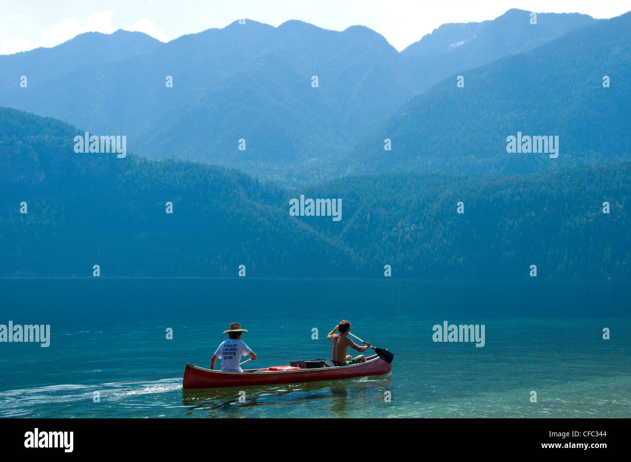 Two men paddling a canoe during summer on the clear, blue waters of