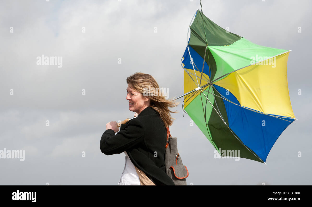 Woman holding onto her umbrella which has blown inside out in a high wind Stock Photo