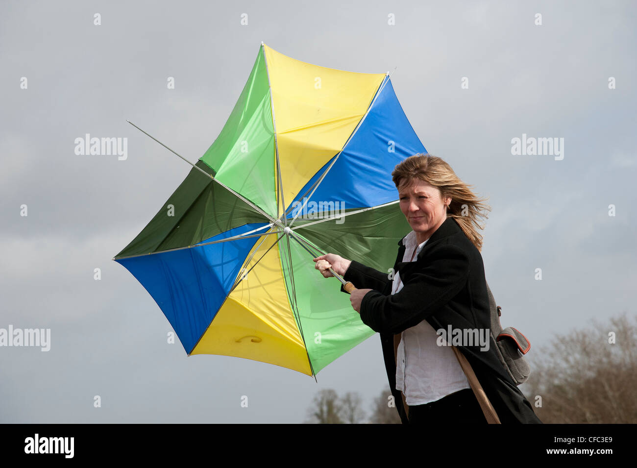 Woman holding onto her umbrella which has blown inside out in a high
