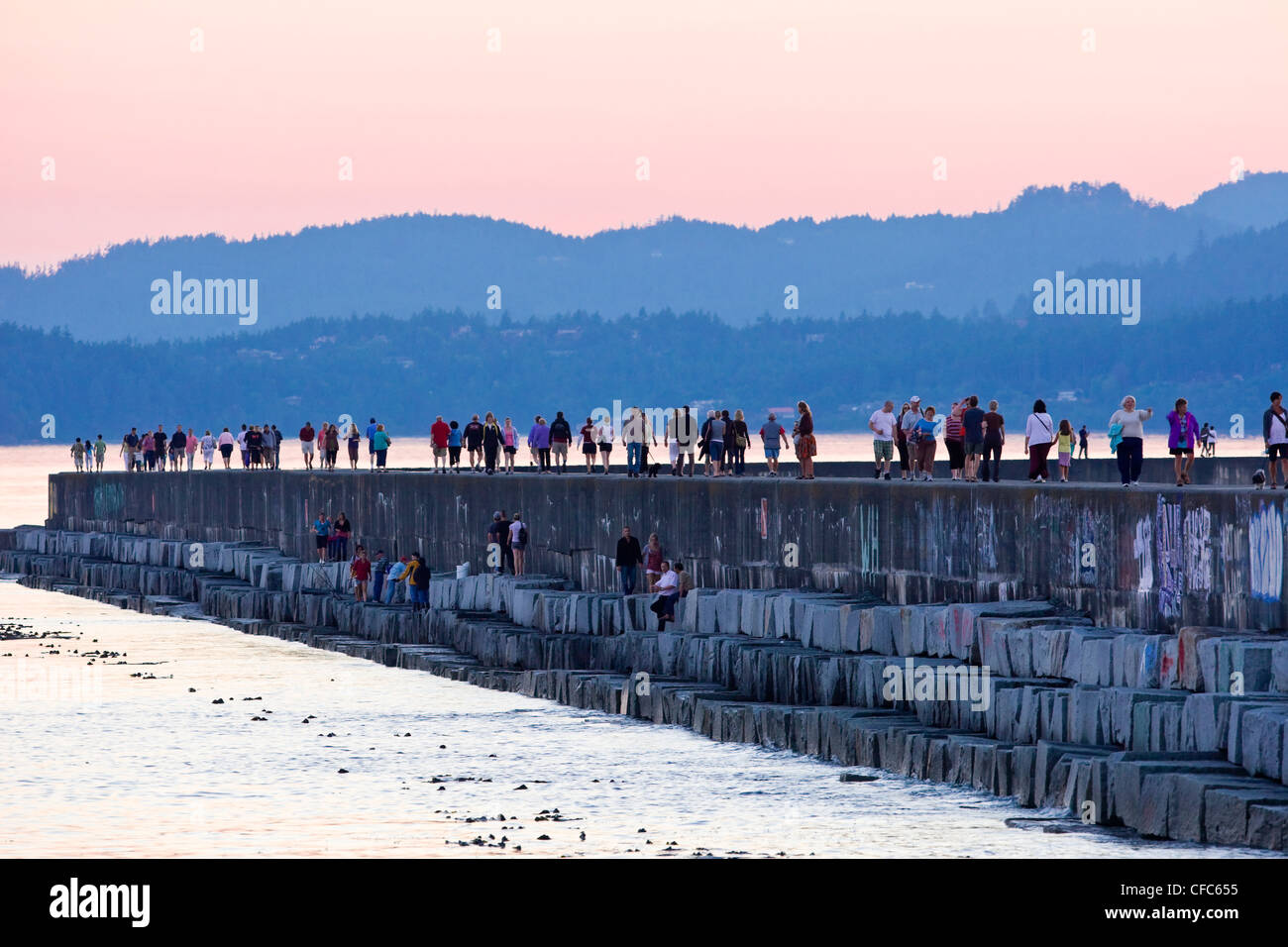 People stroll along Ogden Point waterbreak during Stock Photo