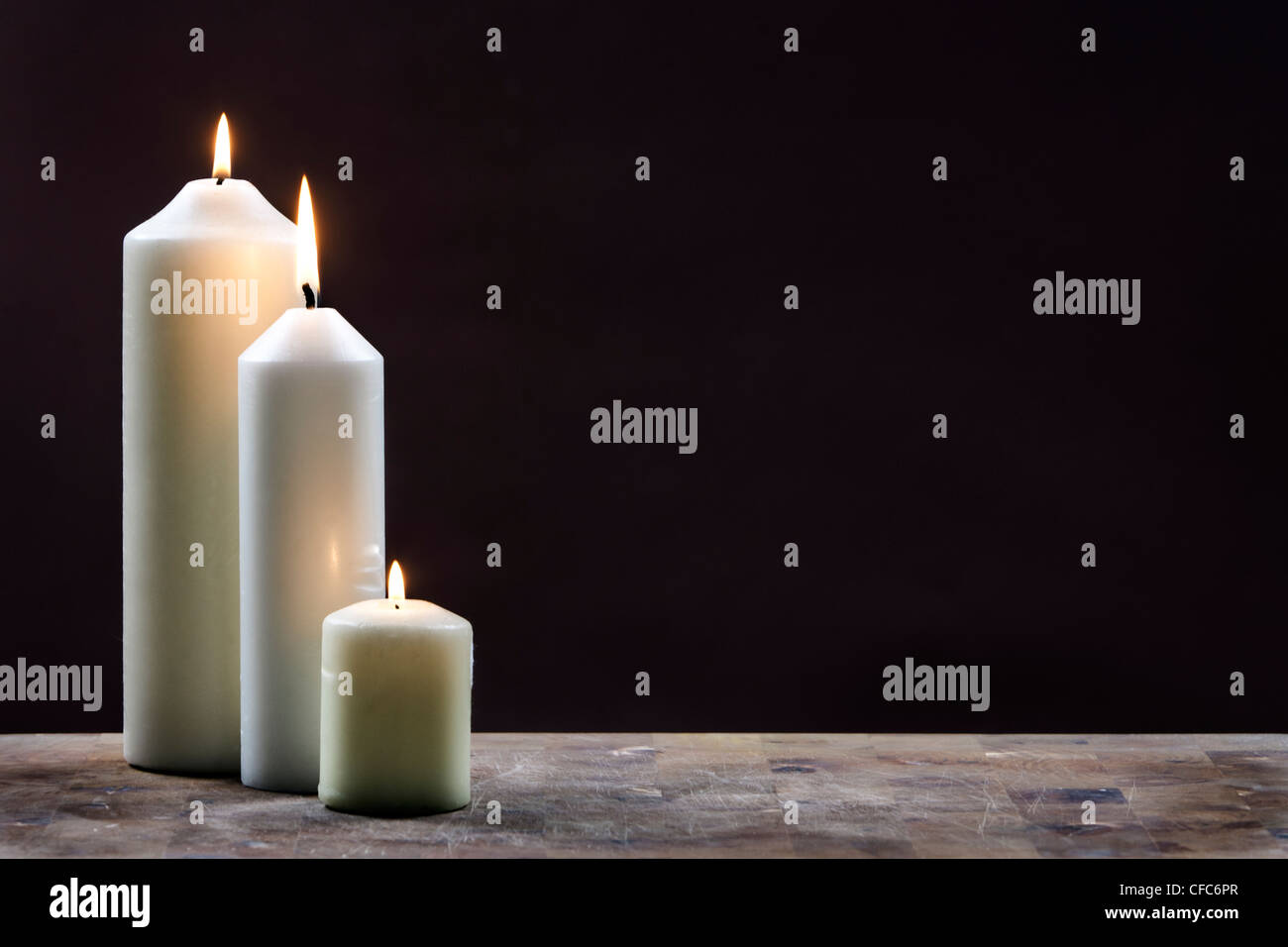 Three Candles against Brown Background Stock Photo