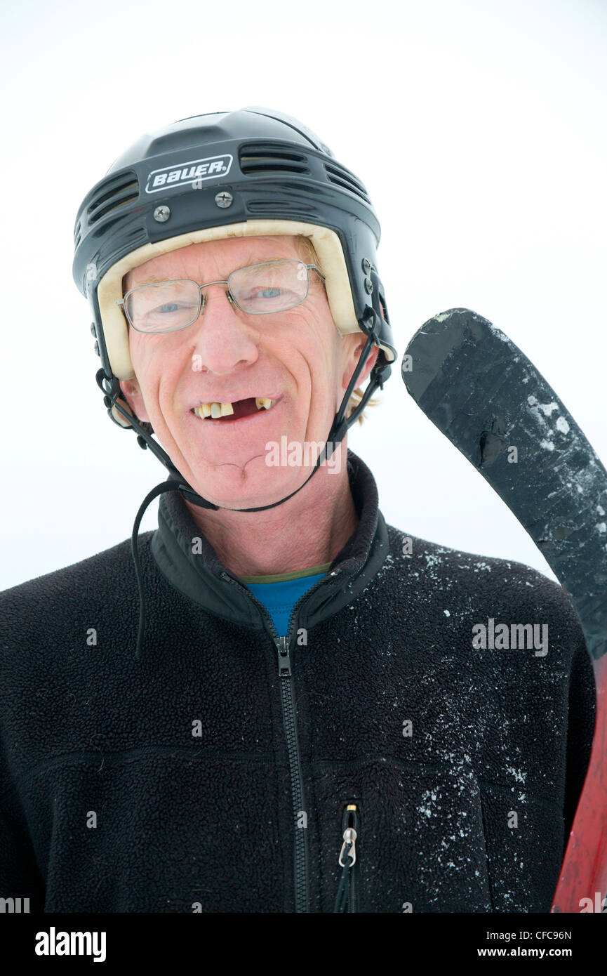 A happy hockey player with missing teeth and a stick smiles during a pond hockey game in Rossland, British Columbia, Canada Stock Photo